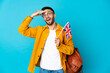 Young caucasian man holding an United Kingdom flag isolated on yellow background doing surprise gesture while looking to the side