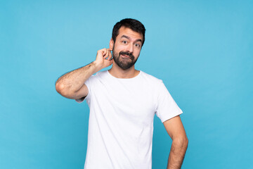 Wall Mural - Young man with beard  over isolated blue background having doubts