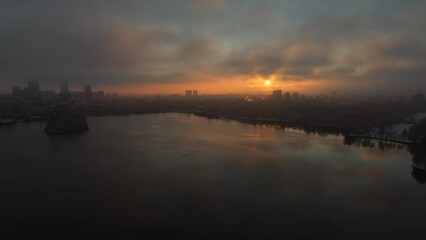 Wall Mural - 4K aerial video in Bucharest. Winter sunrise drone landscape from Herastrau park with amazing sky and its reflection in the lake. Travel to Romania.