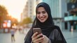 Young muslim woman using smart phone on the street of big city 