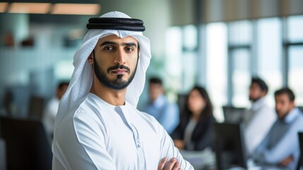 Poster - Serious arab at office wearing kandura looking at front ideal for Middle East business concept. Arabic man inside a corporate establishment with colleagues at the background. 