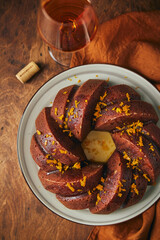 Wall Mural - Delicious homemade pumpkin bundt cake with prunes and sherry, decorated with frosting and zest on a wooden background.