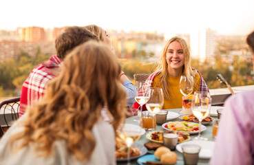 Cheerful friends drinking white wine during roof party