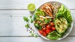 Healthy salad bowl with quinoa, tomatoes, chicken, avocado, lime and mixed greens, lettuce, parsley, on white wood background top view. Food and health, served in the white plate on white wooden table