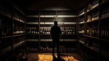 Silhouette Of Man Browsing In Atmospheric Wine Cellar