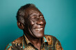 An elderly man with a patterned shirt is smiling with his eyes closed