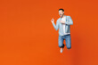 © ViDi Studio - Full body young fun man he wears blue shirt white t-shirt casual clothes jump high point index finger aside on area mock up isolated on plain red orange background studio portrait. Lifestyle concept.