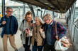 © Marko Geber - Group of senior people using smartphone at train station