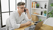 © Krakenimages.com - Attractive young caucasian man, focused business worker, talking on smartphone while working on laptop in office