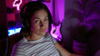 © Krakenimages.com - Young woman with headphones in a gaming room at night illuminated by neon light