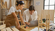 © Krakenimages.com - A man and woman craftsmen collaborating in a woodworking workshop while consulting a laptop.