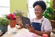 African american woman florist using touchpad holding lavender plant at flower shop