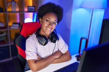 Poster - African american woman streamer smiling confident sitting with arms crossed gesture at gaming room