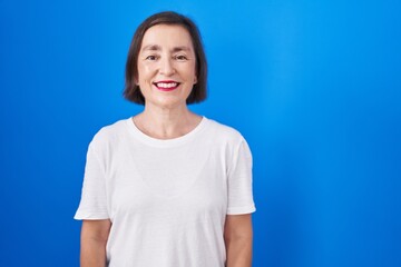 Sticker - Middle age hispanic woman standing over blue background with a happy and cool smile on face. lucky person.