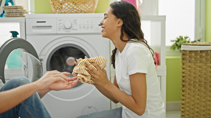 Wall Mural - Happy and beautiful couple confidently smiling together as they wash clothes in their laundry room