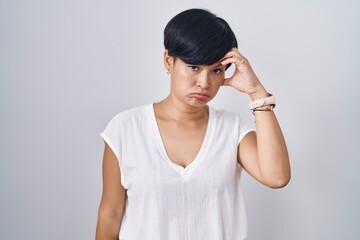 Poster - Young asian woman with short hair standing over isolated background worried and stressed about a problem with hand on forehead, nervous and anxious for crisis