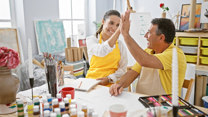 hispanic man and woman artists high five in joy at art studio while drawing on notebook; vibrant cel