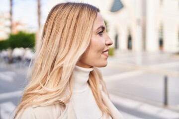 Wall Mural - Young blonde woman smiling confident looking to the side at street