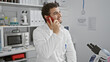 © Krakenimages.com - A smiling man speaking on a phone in a laboratory setting, portraying a professional or scientific concept.