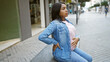 © Krakenimages.com - Tired young pregnant woman, touching her belly, sits in contemplation on an urban street bench, relaxed, balancing the emotion of expectant motherhood and looming maternity ache.