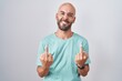 Middle age bald man standing over white background showing middle finger doing fuck you bad expression, provocation and rude attitude. screaming excited