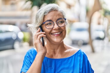 Canvas Print - Middle age grey-haired woman smiling confident talking on the smartphone at street