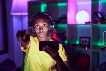 Sticker - African american woman playing video games with smartphone pointing with finger to the camera and to you, confident gesture looking serious