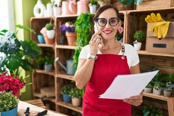 Sticker - Young beautiful hispanic woman florist talking on smartphone reading document at flower shop