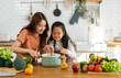 © Art_Photo - Portrait of happy love asian family mother with little asian girl daughter child help cooking food healthy eat with fresh vegetable testing smell soup in a pot with spoon.help mom in kitchen at home