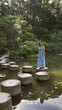 © Krakenimages.com - Beautiful hispanic woman's leisurely summer walk along stone path crossing a lake at traditional heian jingu shrine, kyoto