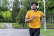© Tetiana - Indian young man doing sports and training in the morning, wearing headphones running in the park