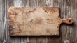 © mashimara - An old wooden cutting board with a used, worn texture on a striped wood table.