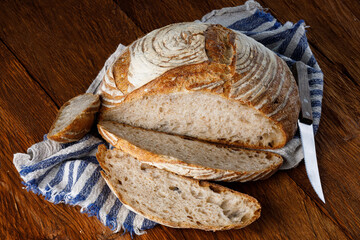 Fototapete - Rustic sourdough bread with cut slices on a wooden table