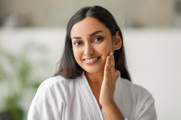 Wall Mural - Closeup of cheerful millennial indian woman touching her face