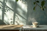Fototapeta  - A steaming cup of tea on a table with shadows from a window. With copy space. Concept of tranquility, calmness, morning routine, and natural ambiance.