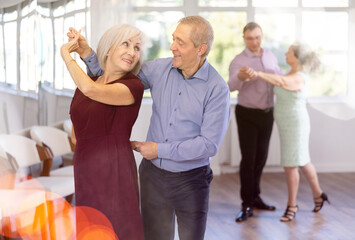 Wall Mural - Senior man and elderly woman are dancing classic version of waltz in couple during lesson at studio. Leisure activities and physical activity for positive people.