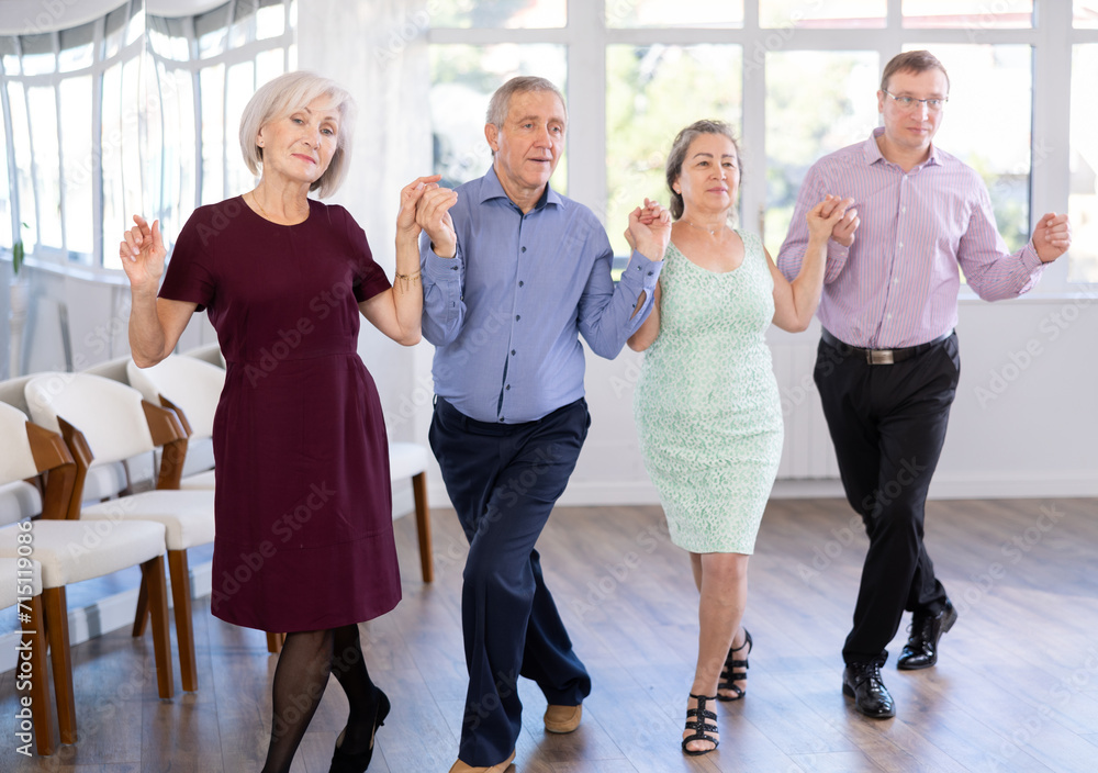 Elderly people with middle aged man holding hands dancing hava nagila