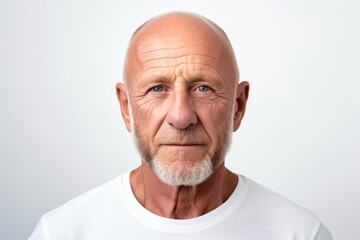 Wall Mural - Portrait of a senior man looking at the camera while standing against white background