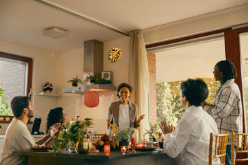 Wall Mural - Group of smiling friends enjoying in conversation and drinking wine during Christmas party at home