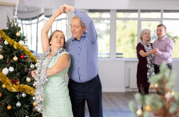 Wall Mural - Smiling elderly woman and her partner successfully perform mesmerizing movements of paso doble dance during celebration Christmas and New Year