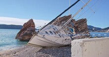  Sailing Yacht Washed Ashore On Embankment Near Cliff, Area Of Crash Site Is Fenced Off With Barrier Tape Picturesque Beach With Broken Ship Lying On Side, Crime Scene, Accident Property Insurance