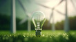 A light bulb stands on grass with wind turbines in the background, symbolizing sustainable green energy solutions.