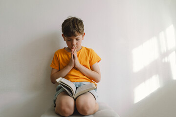 Wall Mural - Christian boy holds bible in her hands. Reading the Holy Bible. Concept for faith, spirituality and religion. Peace, hope.