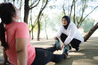 asian woman helping female friend with sprained ankle after exercise