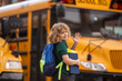 © Volodymyr - Education concept. Schoolkid with backpack and book getting on the school bus. American School. Back to school. Kid of primary school. Happy children ready to study.