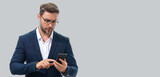 Fototapeta  - Man in suit using smart phone. Portrait attractive cheerful guy using phone, calling on mobile phone. Handsome man with smart phoneon studio isolated background. Banner, copy space.