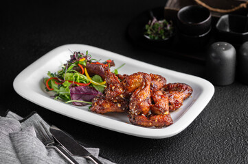 Wall Mural - Plate with buffalo chicken wings with silverware on a black table
