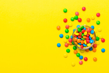 Poster - Multicolored candies in a bowl on a colored background. birthday and holiday concept. Top view with copy space