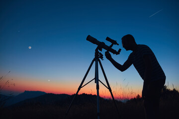 Wall Mural - astronomer looking at the starry skies and crescent moon with a telescope.