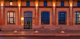 Fototapeta Maki - The façade of the historic building together with the granite pavement illuminated by the light of street lamps